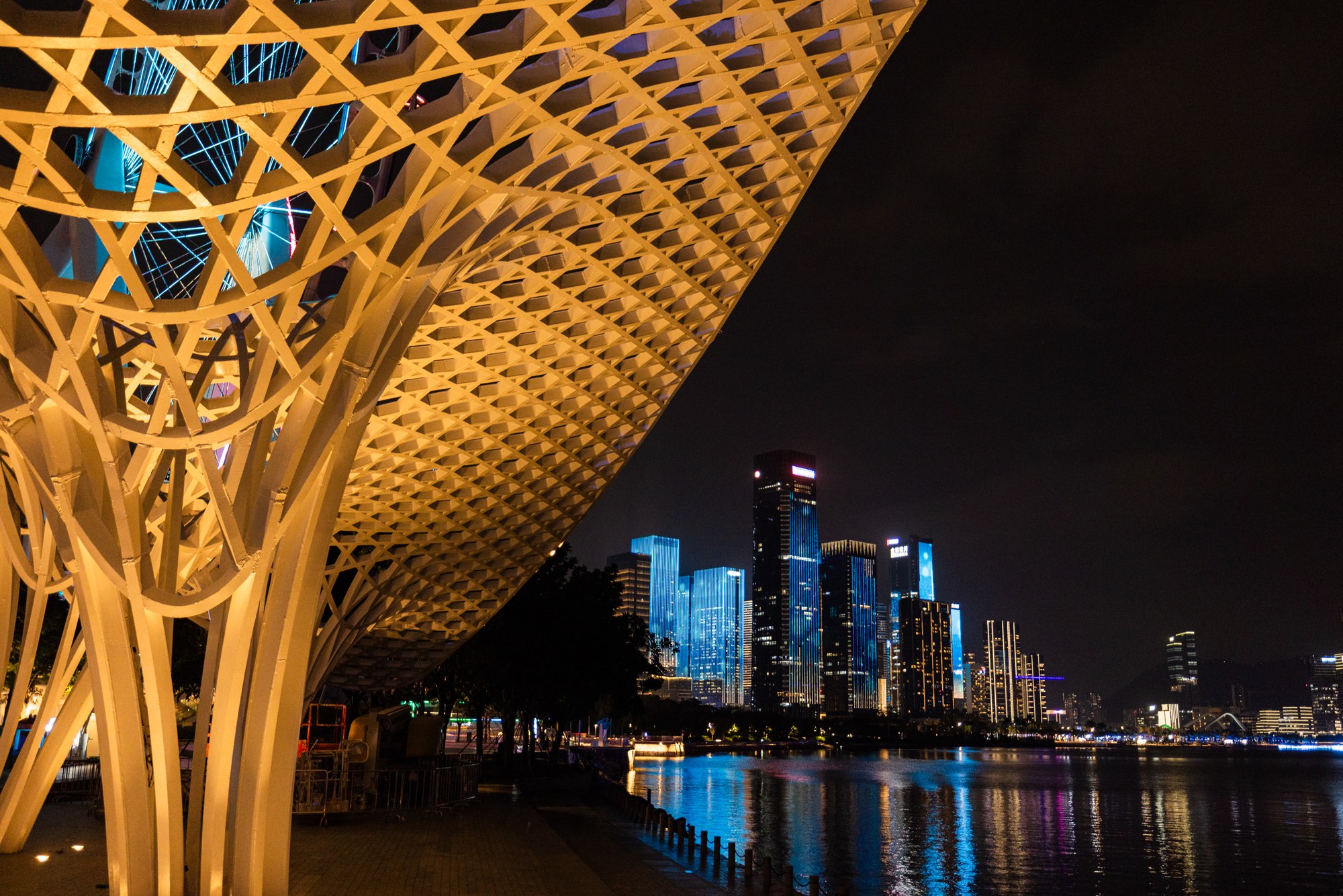 A golden lattice canopy frames a night skyline with water reflection, China