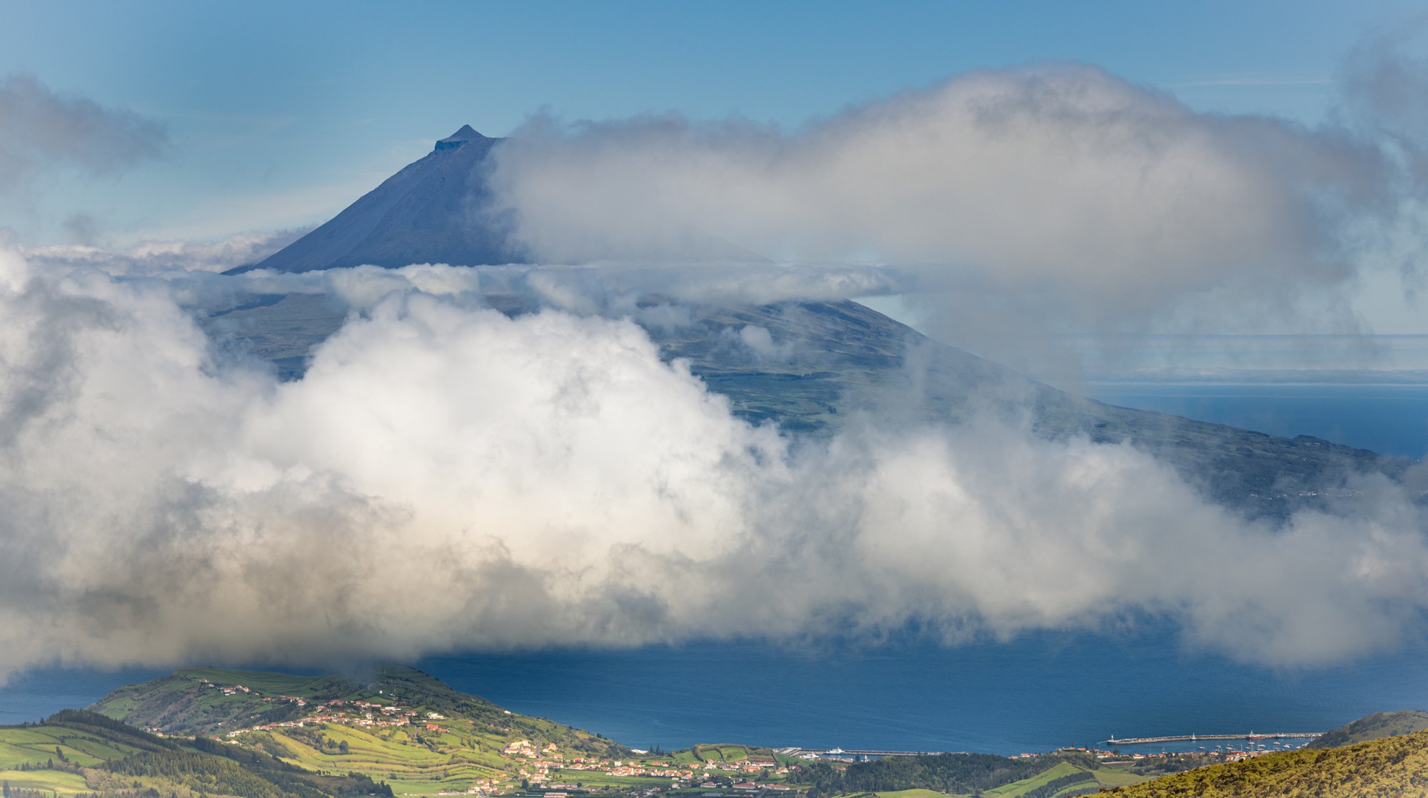The Pico volcano above a blanket of cloud and the coastline, Azores