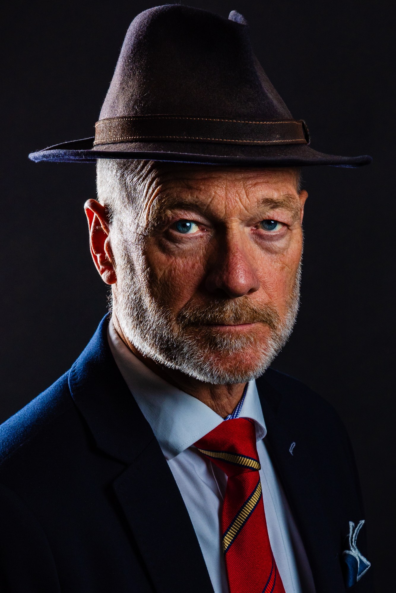 Man with a hat and stubble, sculpted by rim light, studio portrait on black