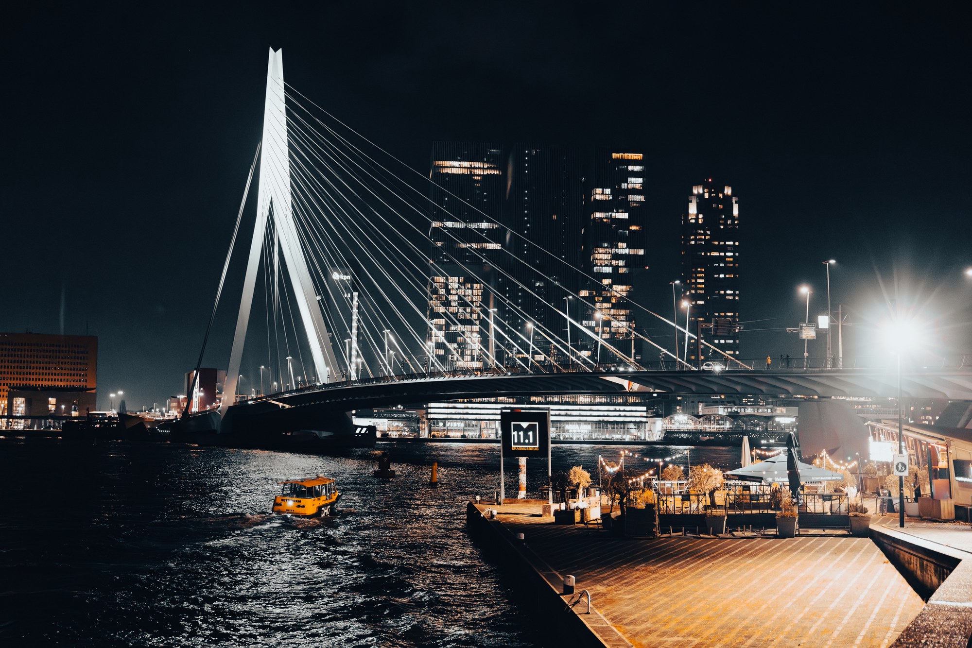 The Erasmus Bridge and the Rotterdam skyline at night, reflected in the water