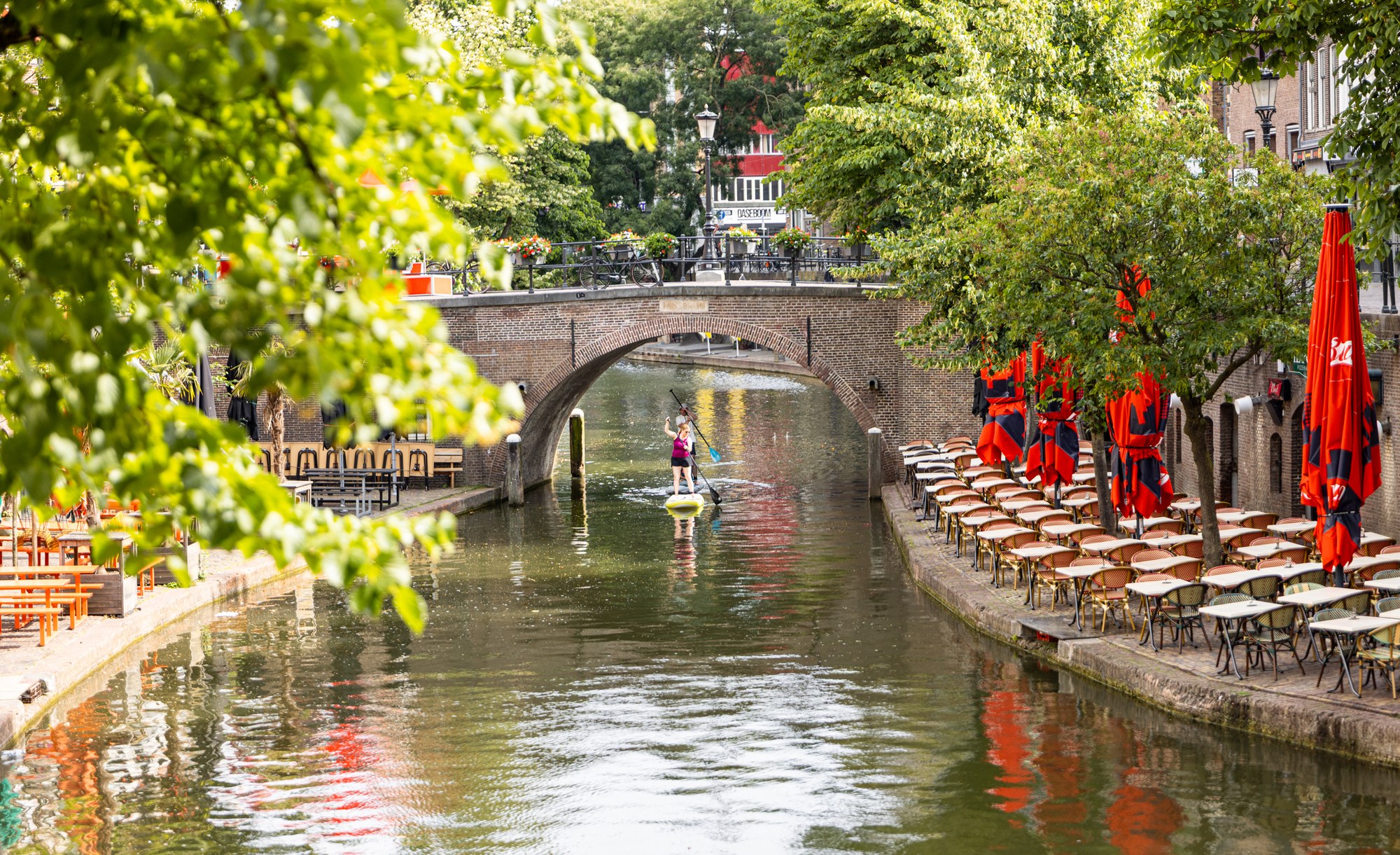 Utrecht canal with a SUP paddler, red parasols and a bridge, Utrecht